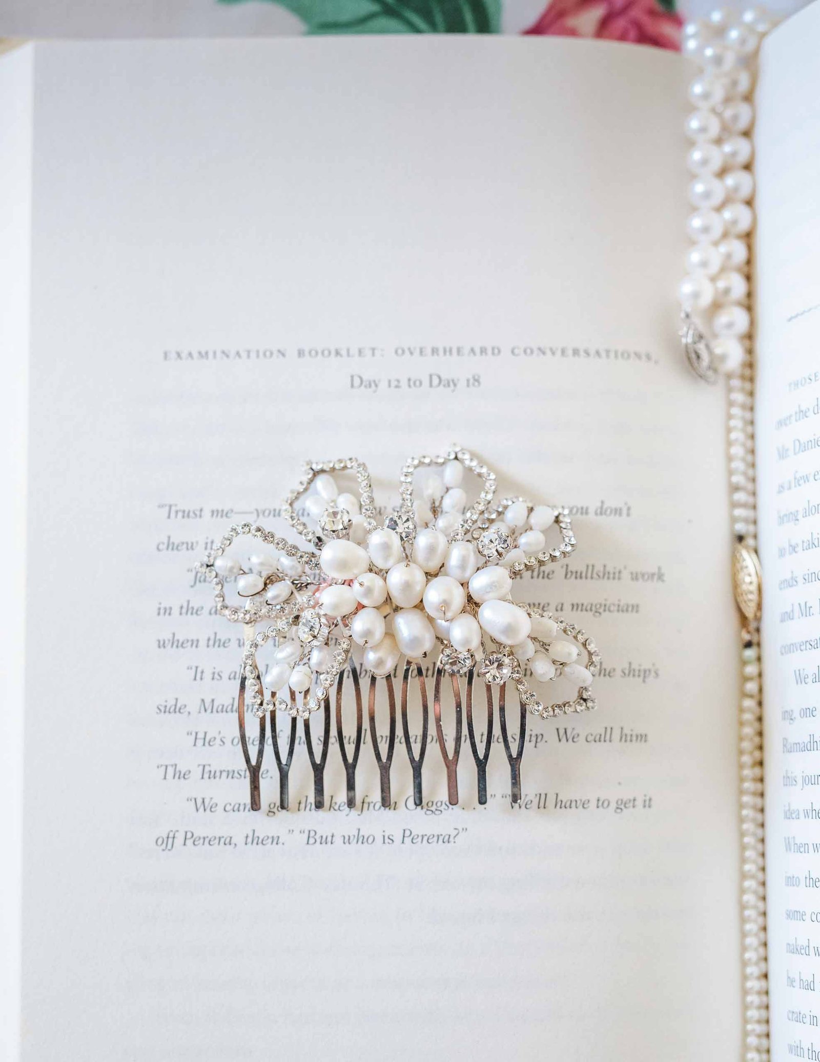 bridal hair clip and pearl necklace placed on an open book