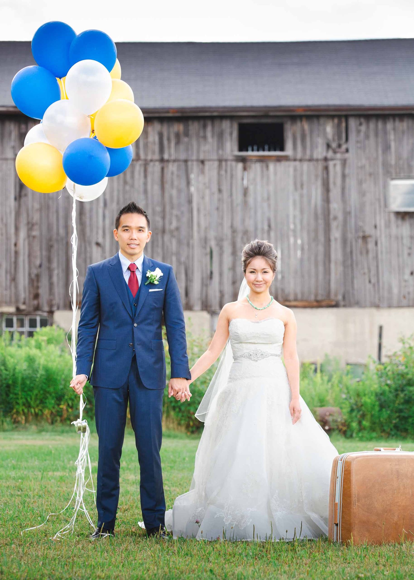 bride and groom on a farm with balloons and luggage