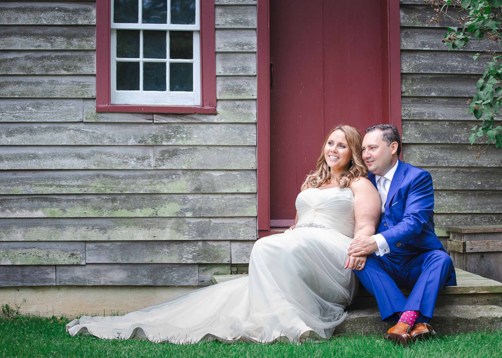 bride and groom sitting in front of barn