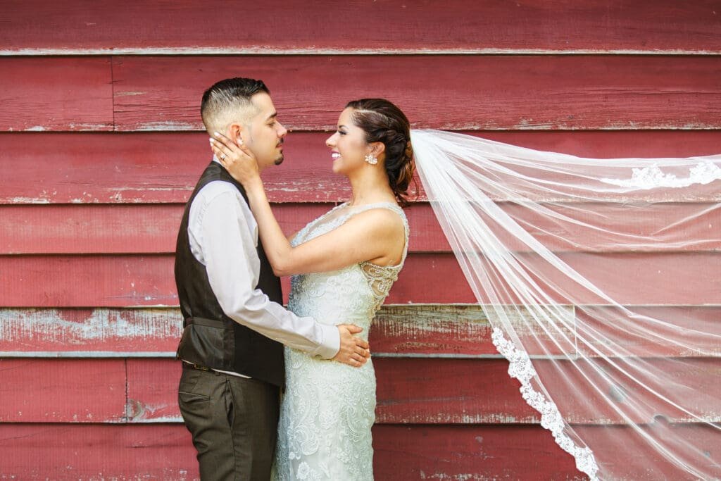 Bride and groom leaning against a red barn