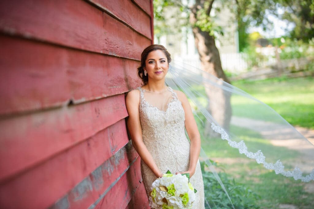 a Bride leaning against a red barn